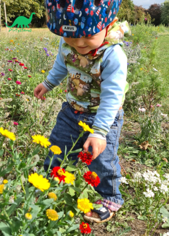 Child outside with flowers wearing cartoon character fabric hoodie