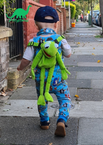 Child walking outside wearing romper suit and bib