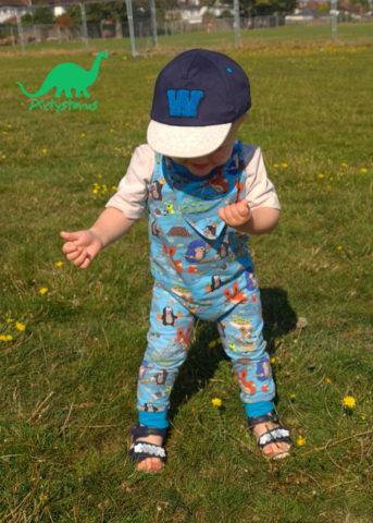 Child outdoors wearing romper suit and bib